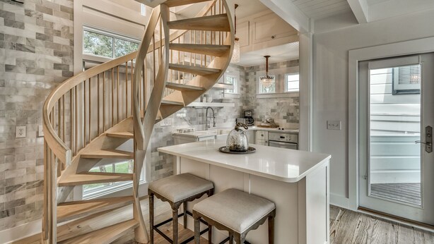 A modern kitchen with a central island, a spiral staircase, and a large window. - Vintage Carriage House - South of 30A! Perfect for young couple or newly-weds! (Rosemary Beach)