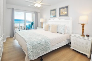 A bedroom with a large bed, a nightstand, a ceiling fan, and a view of the beach. - Gulf Dunes 309 • Direct Ocean View from 4th Floor, Beautiful Beach Condo, Free Beach Service (Fort Walton Beach)