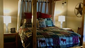 Un lit à baldaquin avec une couvre-lit à carreaux orné de motifs animaliers, deux lampes de chevet et une décoration en forme d’étoile sur le mur.