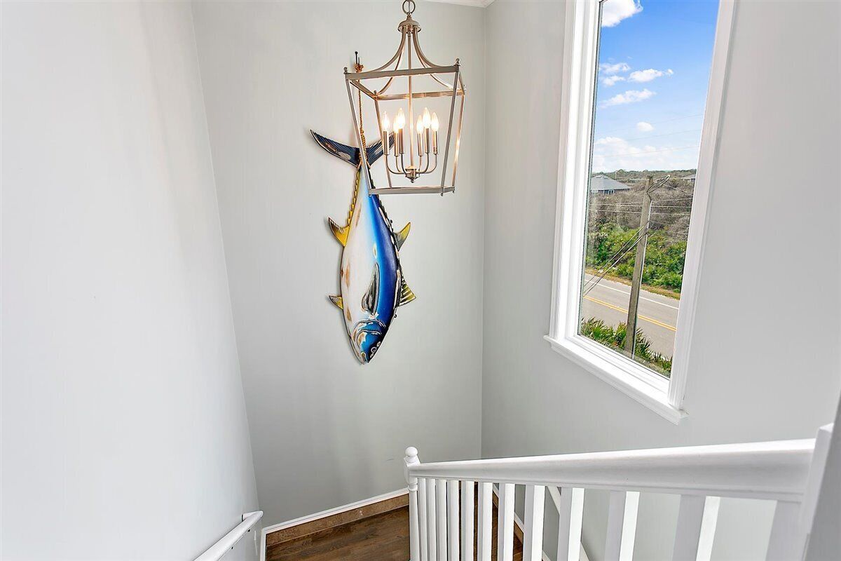 A staircase with a white railing, a wall-mounted fish sculpture, and a hanging lantern.