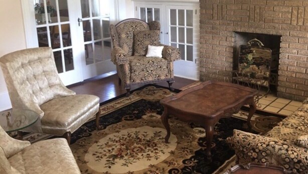 A traditional living room with a fireplace, two armchairs, a sofa, and a coffee table.