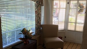 A living room with a sofa, a chair, a small table with a plant, and a patterned rug.