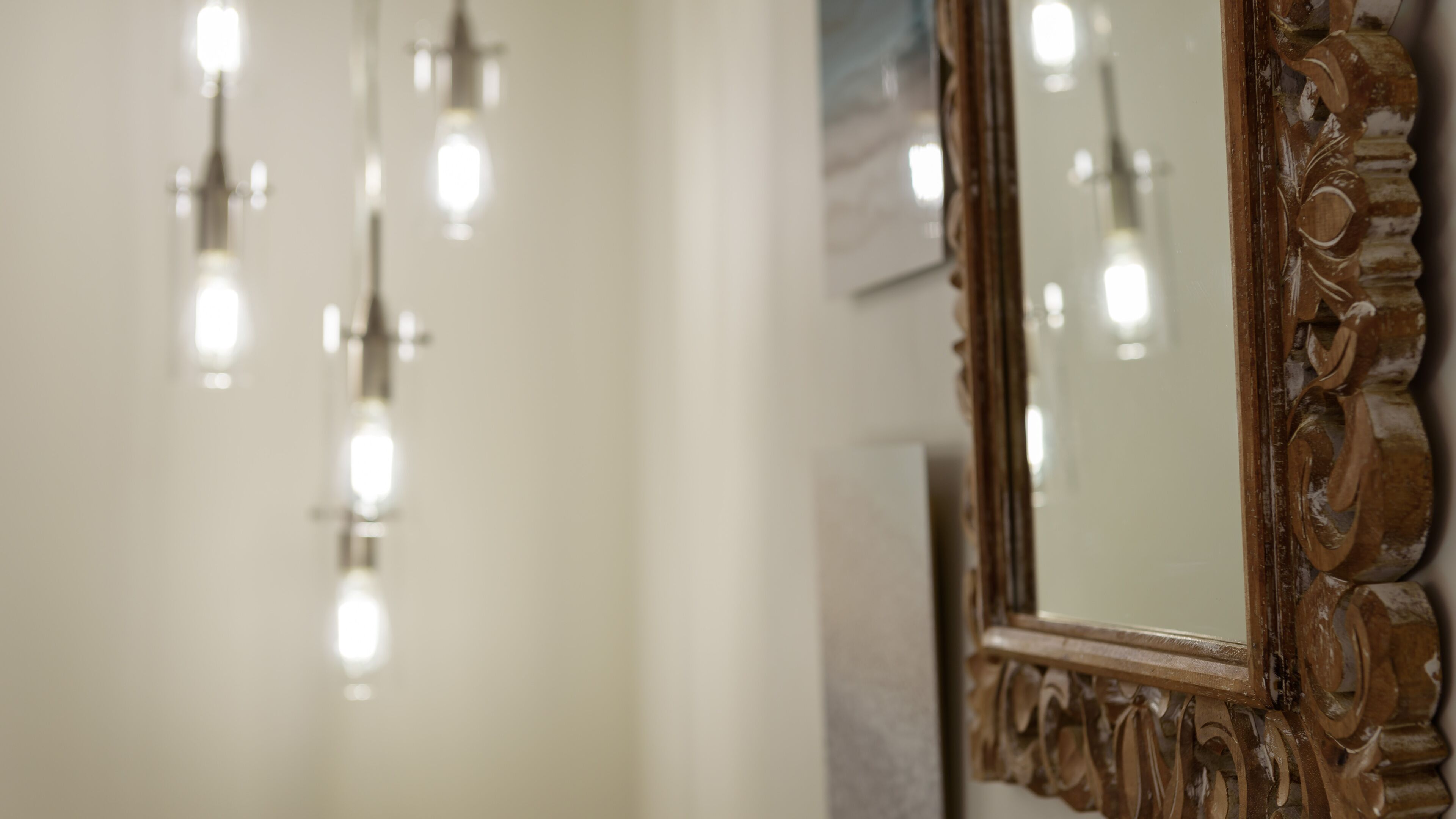 Un miroir orné de sculptures complexes en bois et un luminaire doté de plusieurs ampoules.