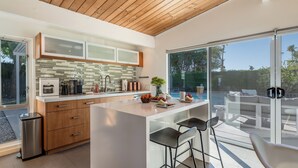 Una cocina moderna con una isla grande, armarios de madera y vista al patio exterior.