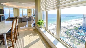 Amplia sala de estar con un gran ventanal con vista a una playa y muelle.