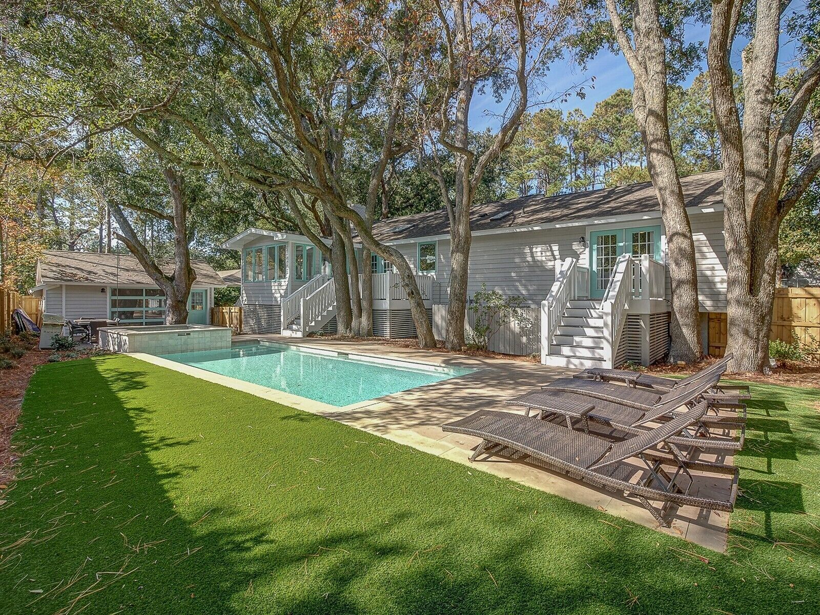 Ein Wohnhaus mit Schwimmbad, gepflegtem Rasen und einer Treppe, die zu einer Veranda führt.