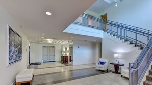A spacious lobby with a staircase, a bench, and a view to a balcony. - Rare 4 Bd / 3 Ba 2,900+ Sq ft Oceanfront Luxury Condo w Huge Balcony & Grill (Daytona Beach)