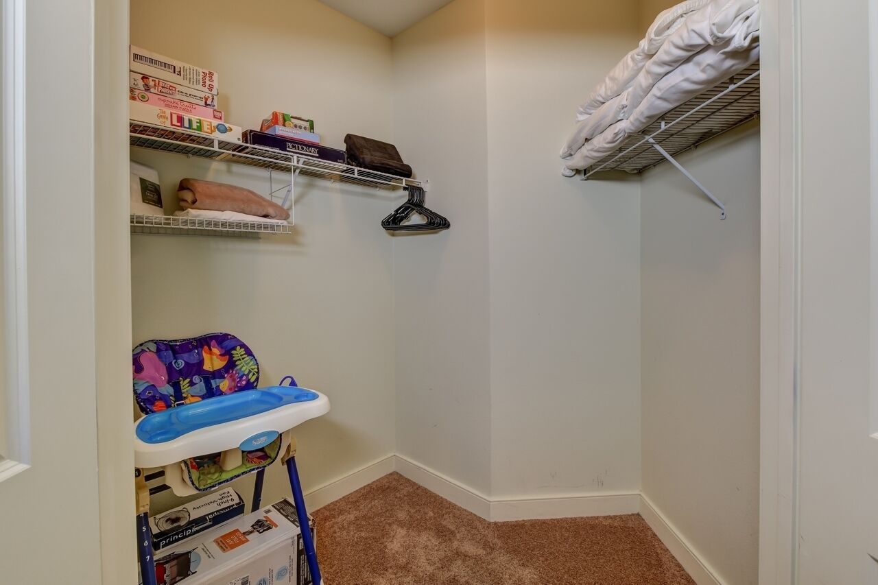 A corner room with a bunk bed, a shelf with books and a blanket, and a baby changing station.