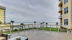 A balcony with a view of the ocean, a table with a turtle sculpture, and a chair. - Rare 4 Bd / 3 Ba 2,900+ Sq ft Oceanfront Luxury Condo w Huge Balcony & Grill (Daytona Beach)