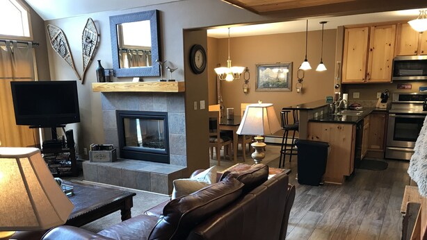 Una sala de estar con chimenea, sofá de cuero y televisor.