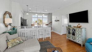 A modern kitchen with a central island, white bar stools, and pendant lighting. - Poolside House w/ Ocean Views, Steps from Beach & Restaurants (Atlantic Beach)