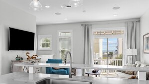A modern kitchen with a large window, a flat-screen TV, and a balcony with a view. - Poolside House w/ Ocean Views, Steps from Beach & Restaurants (Atlantic Beach)