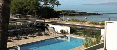 A swimming pool with lounge chairs and a view of the ocean.