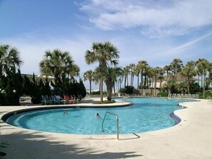 A swimming pool with palm trees and lounge chairs.