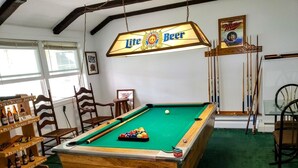 A pool table with a beer sign above, wooden chairs, and a billiards rack. - Lake House on Seneca Lake with Private Dock (Romulus)