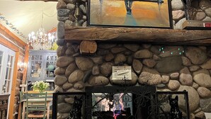 Una chimenea de piedra con un cuadro encima, una pared de piedra y una araña.