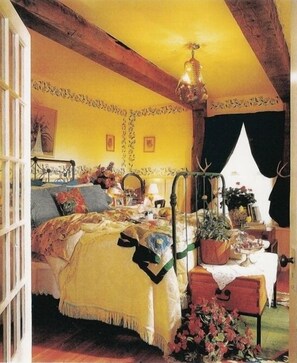 A cozy bedroom with a bed, bedside table, lamp, and a window with curtains.