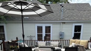 Una terraza con mobiliario exterior, incluyendo sofás y sillones, y un paraguas grande.