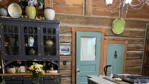 Una cocina rústica con armarios de madera, una mesa de comedor y una mascota cerca de la puerta.