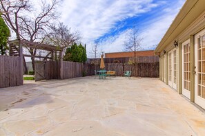 Un patio de piedra con una pérgola y mobiliario exterior.