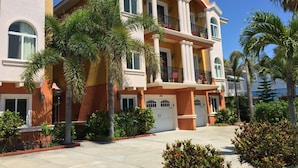 Un edificio residencial de varios pisos con balcones, ventanas amplias y un jardín bien cuidado.