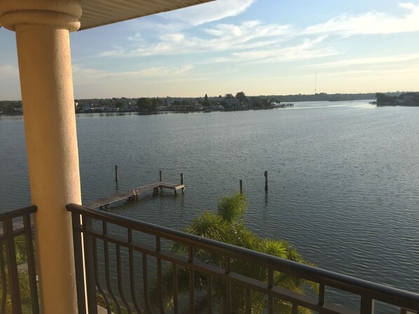 A view of a calm lake from a balcony with a wooden dock extending into the water.
