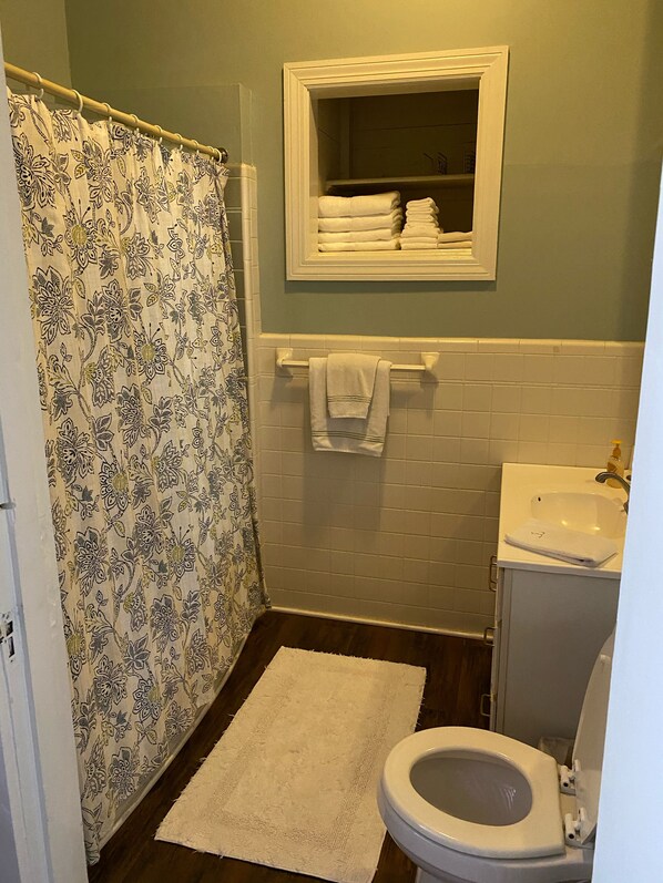 A bathroom with a shower curtain, a white sink, a toilet, and a small mirror above the sink.