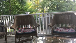 A covered porch with wicker chairs and a glass table.