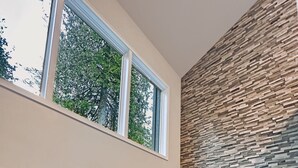 Ein modernes Wohnzimmer mit Kamin, großen Fenstern und einer Steinwand.