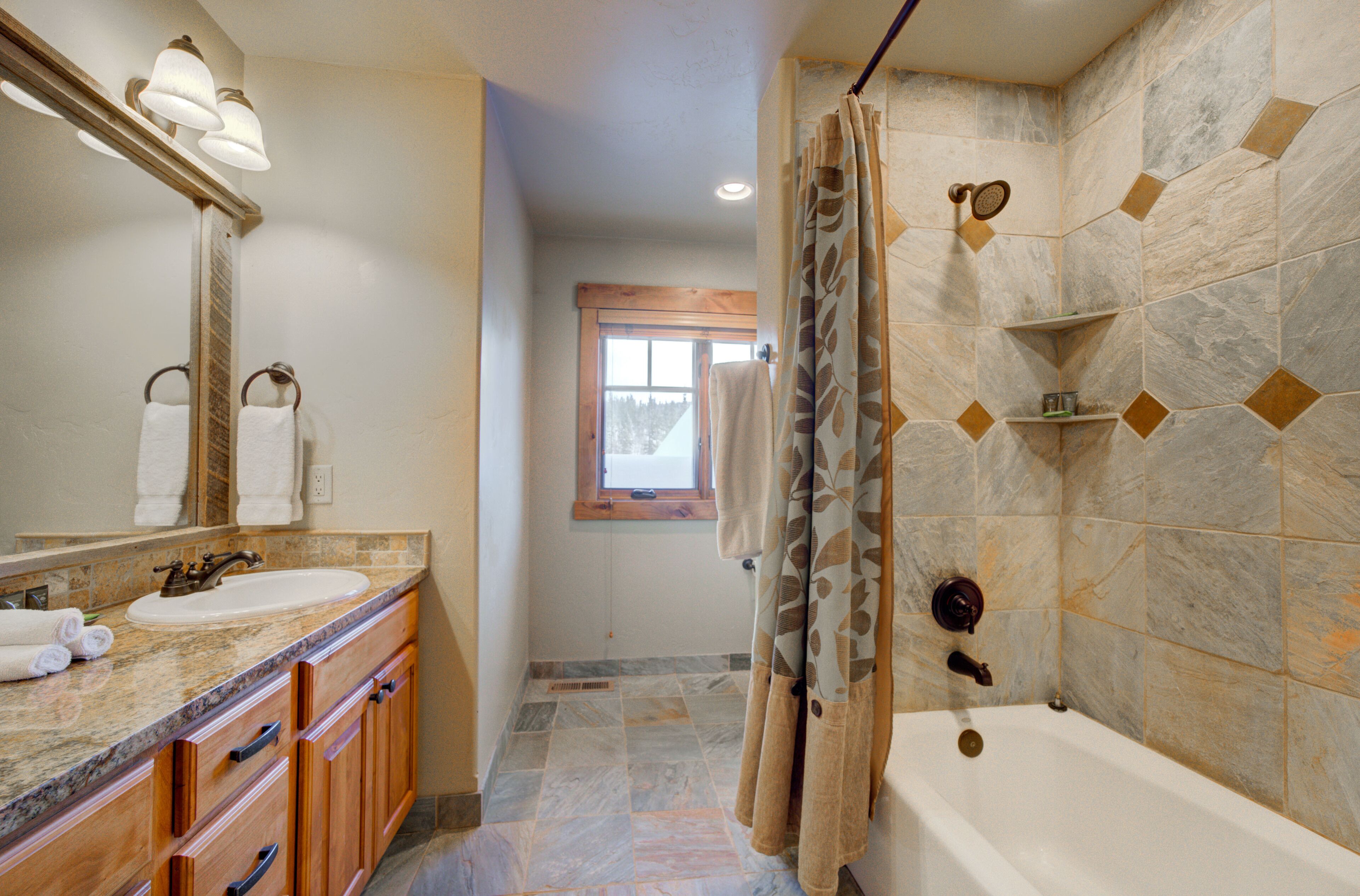 A bathroom with a sink, mirror, and shower area.