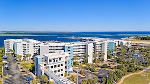 A coastal hotel complex with multiple buildings, a parking lot, and a view of the ocean.