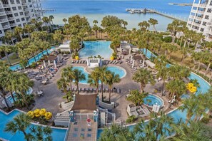 Un resort con varias piscinas, palmeras y vistas al océano.