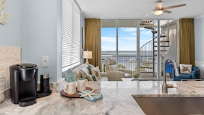 A modern living room with a large window, a coffee maker, and a view of the ocean.
