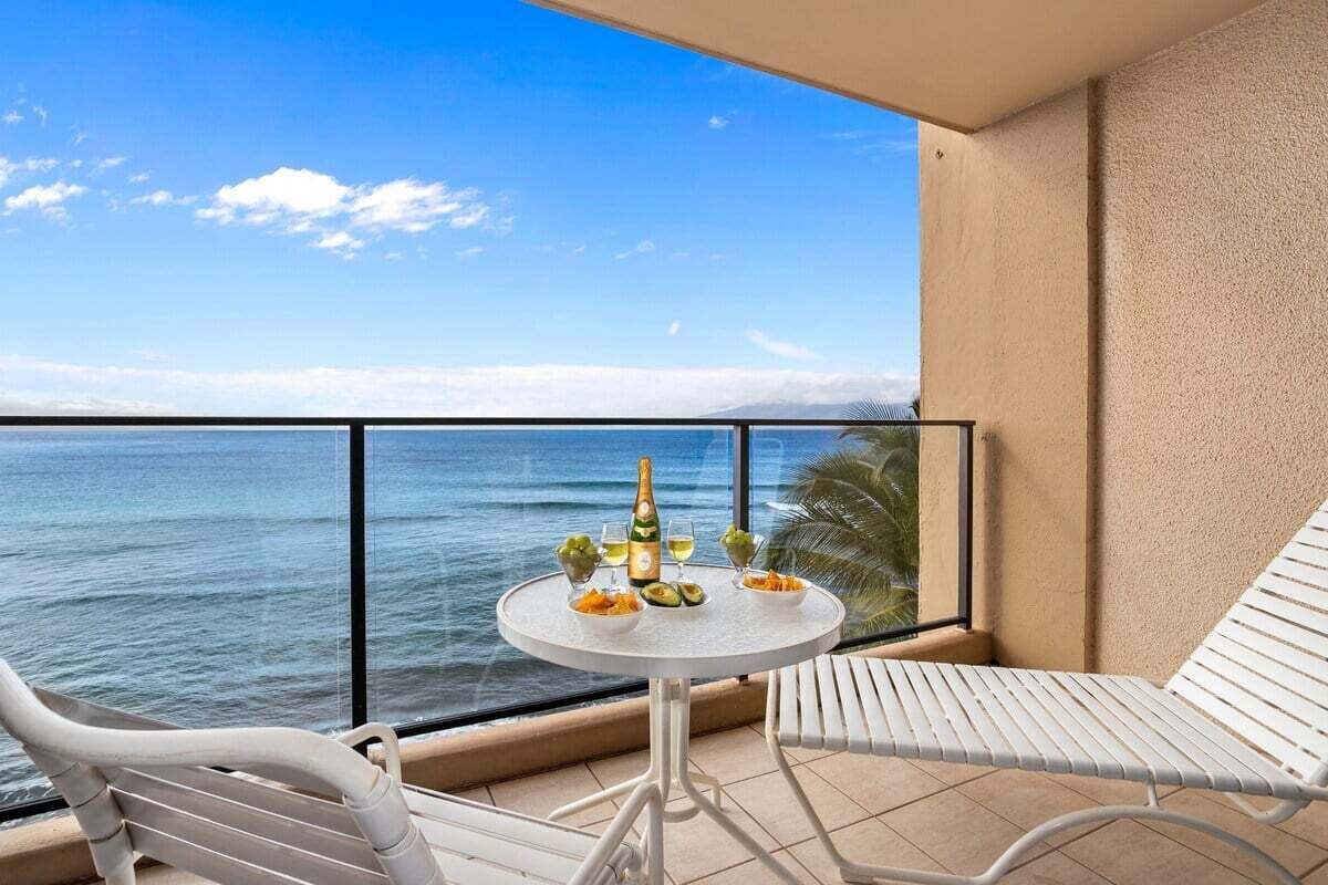 A balcony with a table set for two, overlooking the sea.