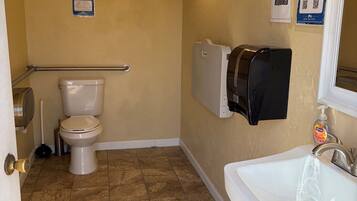 Une salle de bain équipée de toilettes, d’un lavabo et d’un distributeur d’essuie-tout.