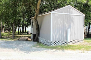 A single-story shed with a sloped roof, a small window, and a lattice base. - Waterfront Hideaway Cabin | Private Lake Access & Stunning Views (Little Elm)