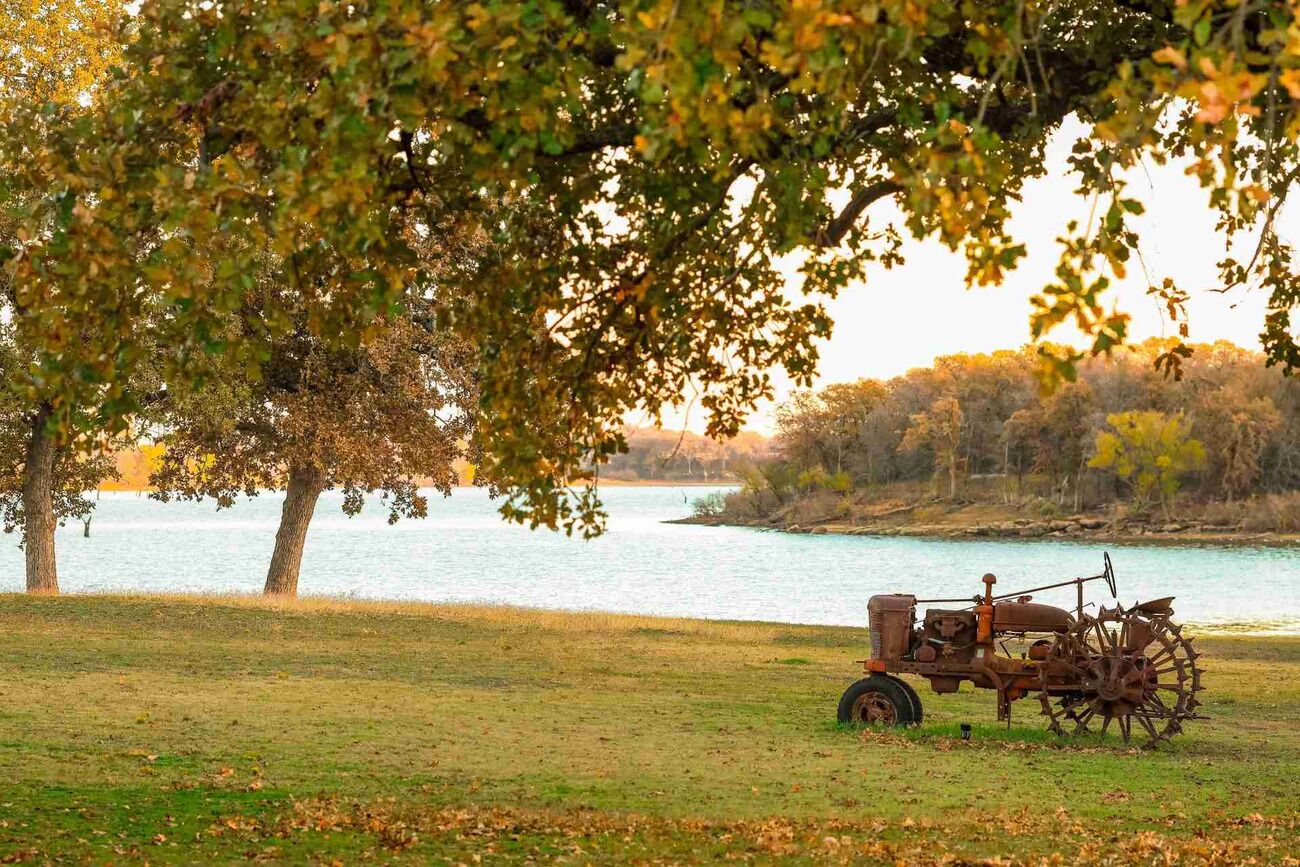 Un tracteur près d’une étendue d’eau, entouré d’arbres et d’herbe.