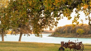 Un tracteur près d’une étendue d’eau, entouré d’arbres et d’herbe.