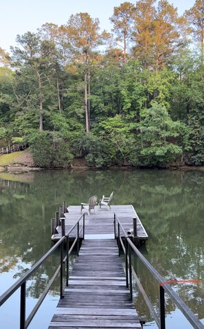 Une jetée en bois s’étendant sur un lac paisible, entourée d’une forêt dense.