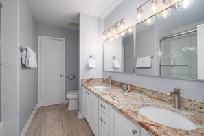 A modern bathroom with two sinks, a large mirror, and a shower.