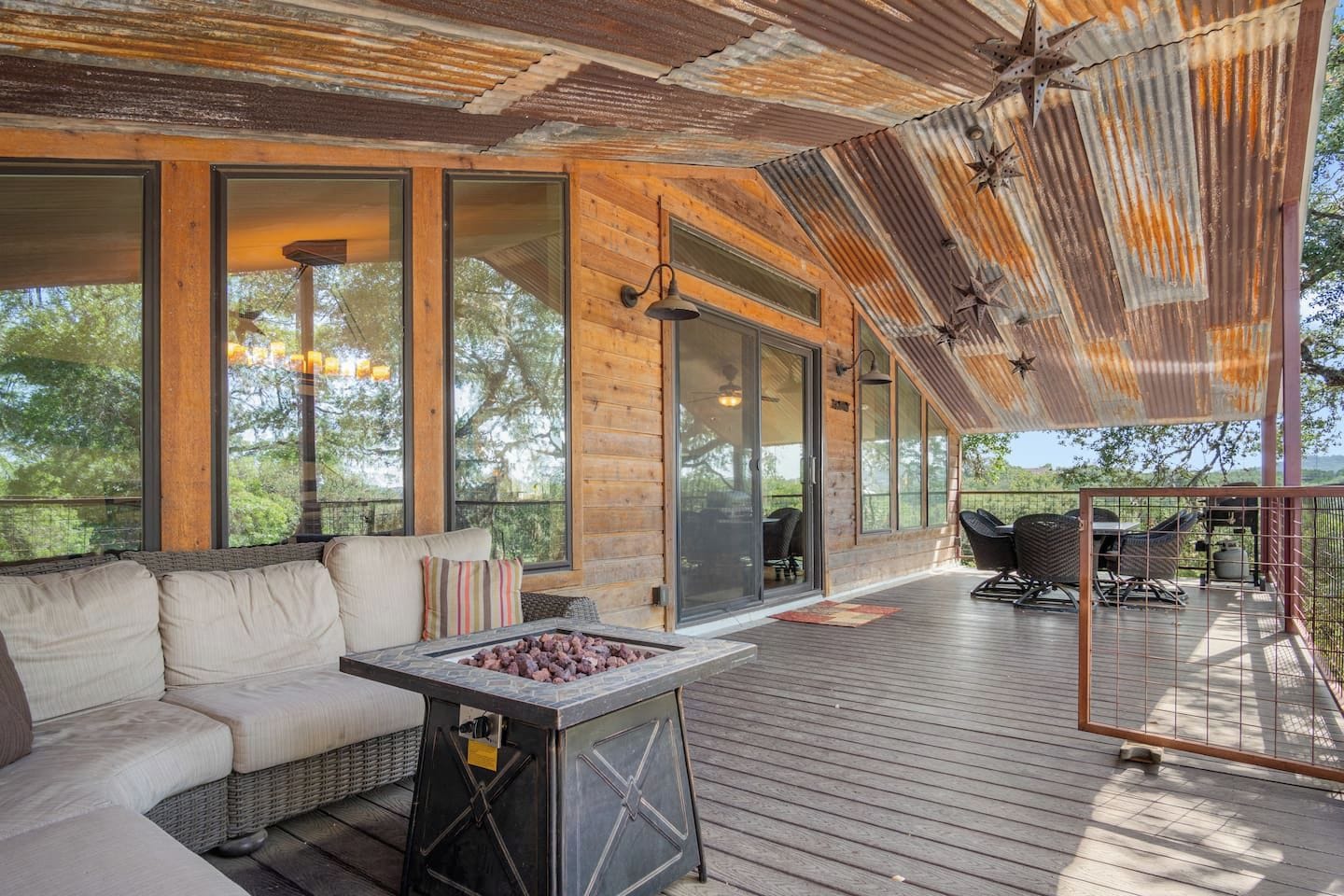 A covered outdoor deck with a fire pit, seating area, and large windows.