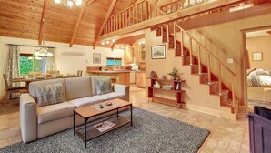 A spacious living room with a high ceiling, wooden staircase, and a cozy seating area. - Cozy, clean, updated cabin w/hot tub, fireplace, fire pit, BBQ, smart TV (Packwood)