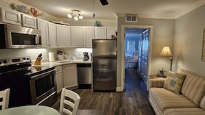A modern kitchen with white cabinets, stainless steel appliances, and a wooden dining table.