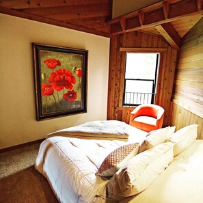 A bedroom with a bed, a chair, a window, and a painting on the wall. - Ocean views. Long stay discount. Short walk to Shell beach, dog friendly. (Sea Ranch)