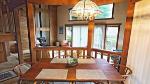 A wooden dining area with a table, chairs, a chandelier, and large windows. - Ocean views. Long stay discount. Short walk to Shell beach, dog friendly. (Sea Ranch)