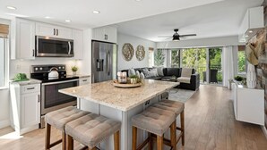 A modern kitchen with a central island, stainless steel appliances, and a dining area with a sofa and chairs. - Key Largo Villa, Kawama P6, 3/3 (Key Largo)