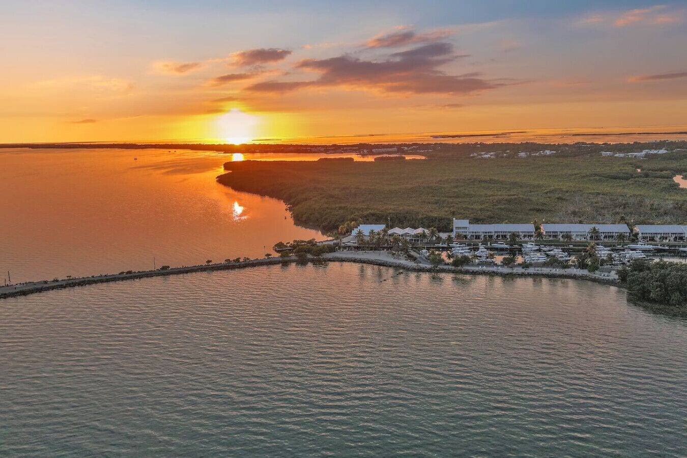 A coastal resort with a marina, beachfront villas, and a pier extending into the water.