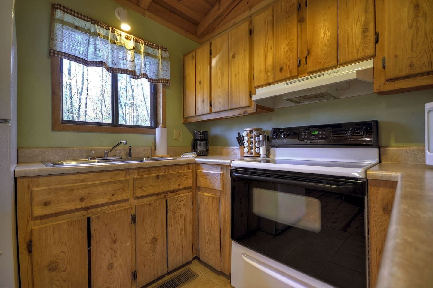 Una cocina con armarios de madera, estufa y lavamanos.