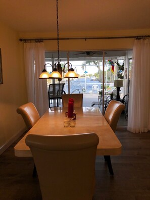 Enjoy meals with a view of the marina and water from this dining area, featuring a long table and four chairs.