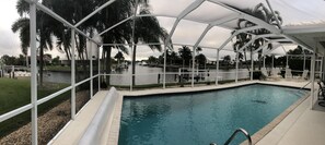 Relax by the pool with a clear view of the surrounding landscape, surrounded by palm trees and a tranquil body of water.